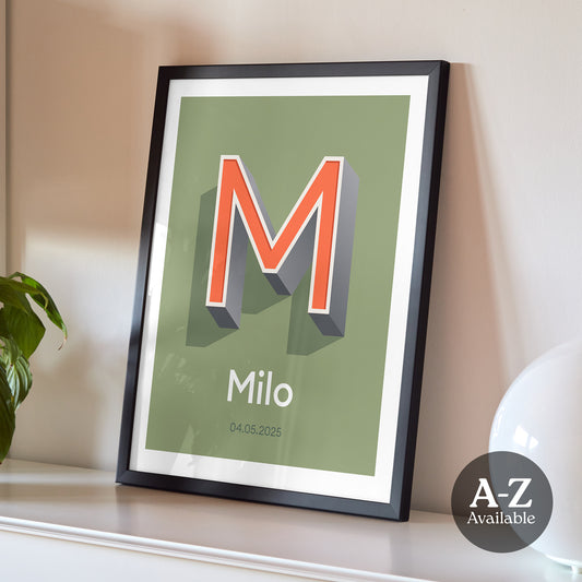 A personalised name and date print from Alf and Bet with a Khaki Green base colour and 3D letter with Orange infill